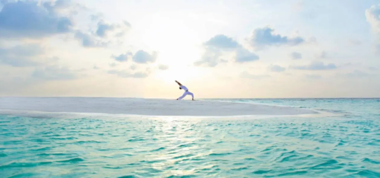 Man doing yoga on sandbank at Baros Maldives